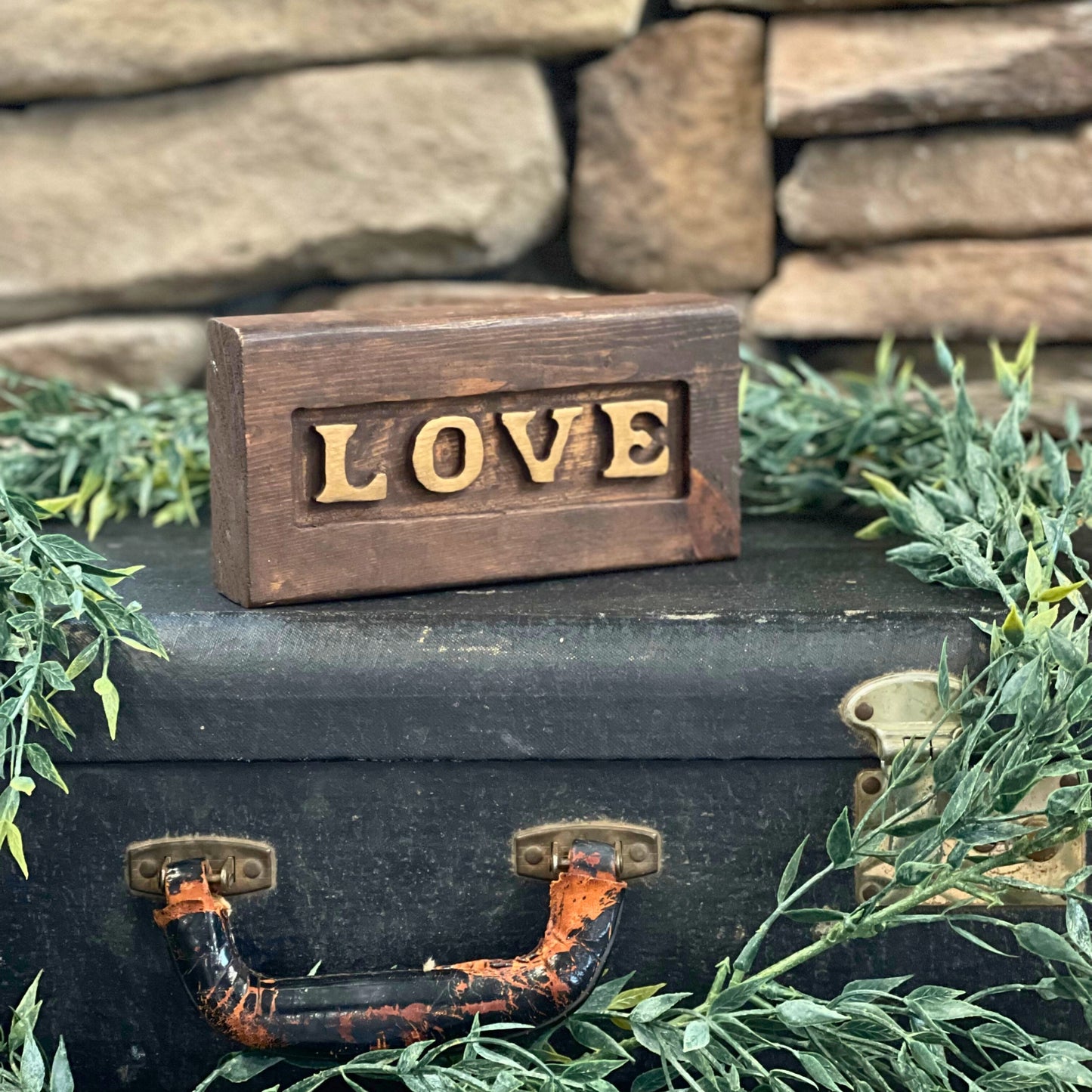 Crafted from dark-stained wood with a beautifully carved 'Love' lettering, this piece features a subtle gold hue that gives it a soft, timeless glow - Picture Perfect Rentals