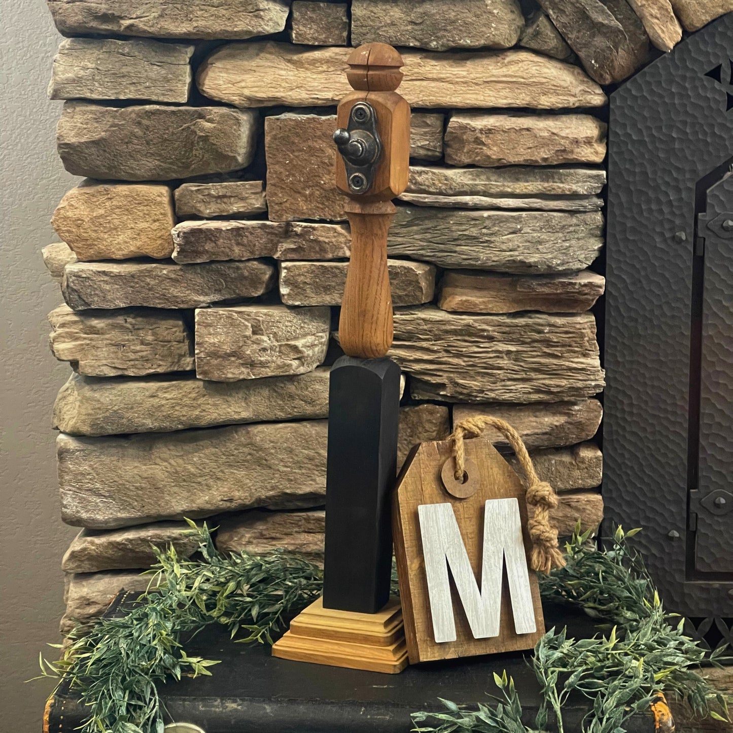 Unique wood sign holder with a wood sign with a metallic letter "M" on it leaning up against it for a styled photo - Picture Perfect Rentals