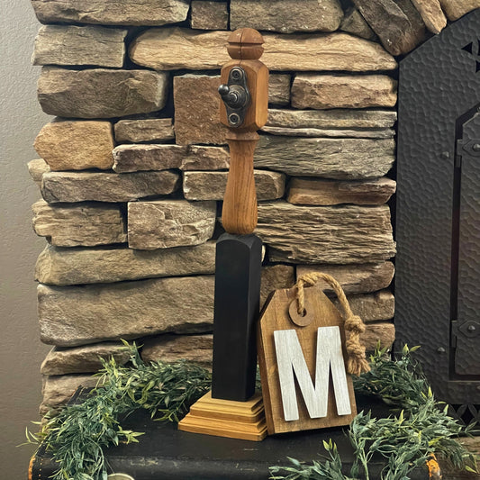 Unique wood sign holder with a wood sign with a metallic letter "M" on it leaning up against it for a styled photo - Picture Perfect Rentals