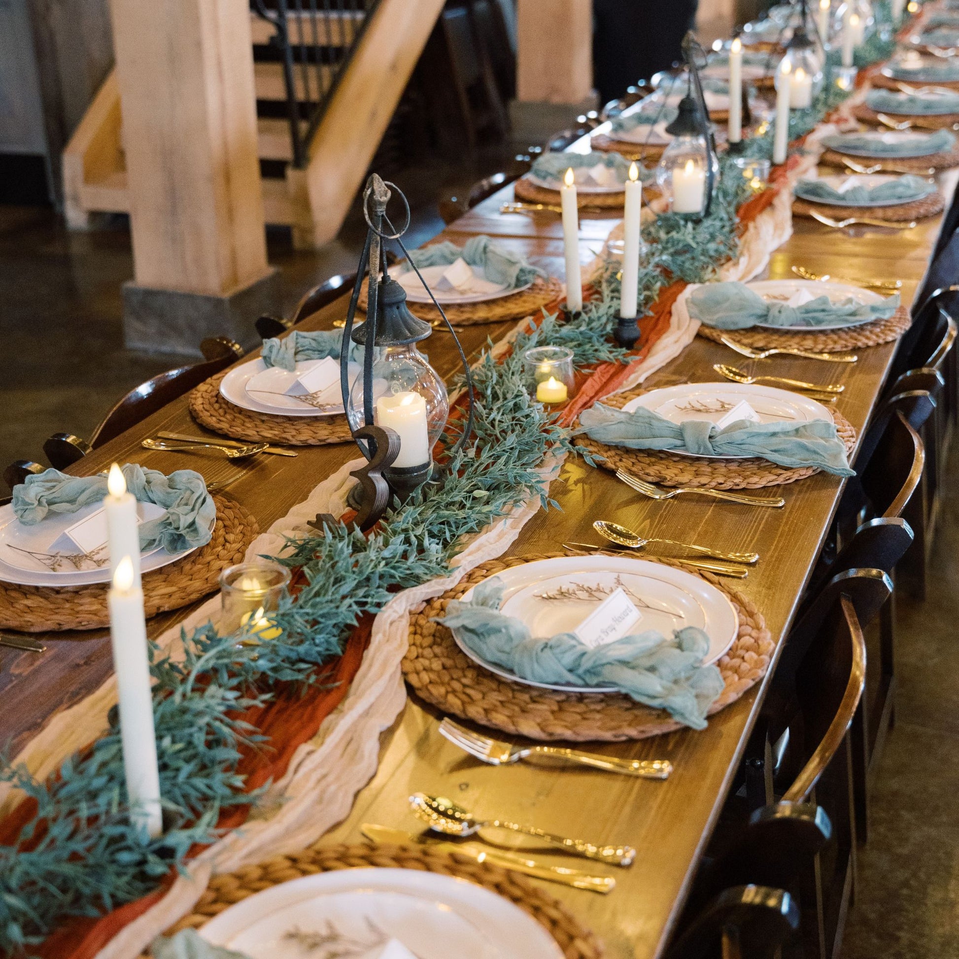 Wedding table setting with table runners, garland, lanterns, and candles - Picture Perfect Rentals