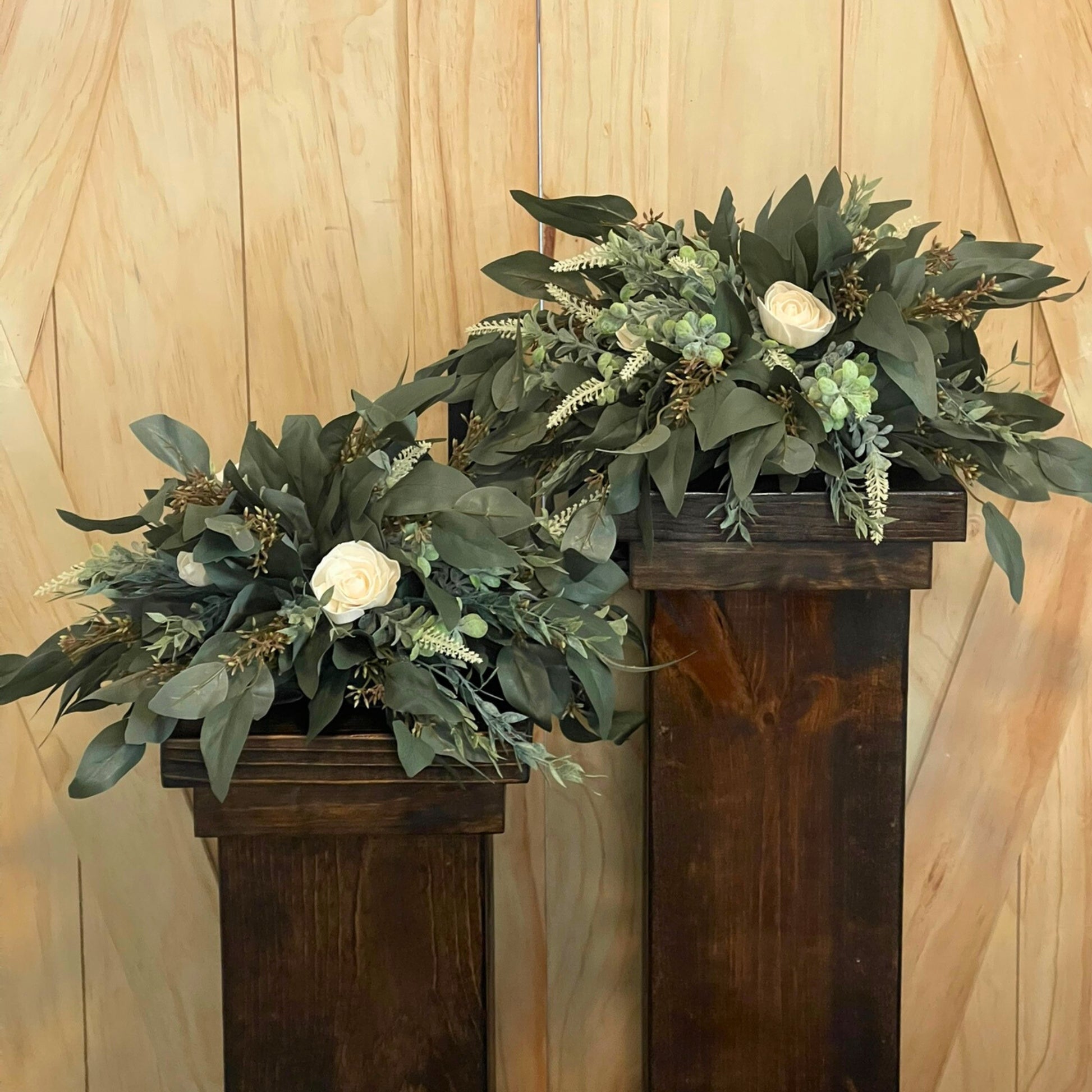 Seeded Eucalyptus and Cream Rose Centerpieces on Dark Stained Wood Pedestals for Rent - Picture Perfect Rentals Event Rentals in Wichita, KS