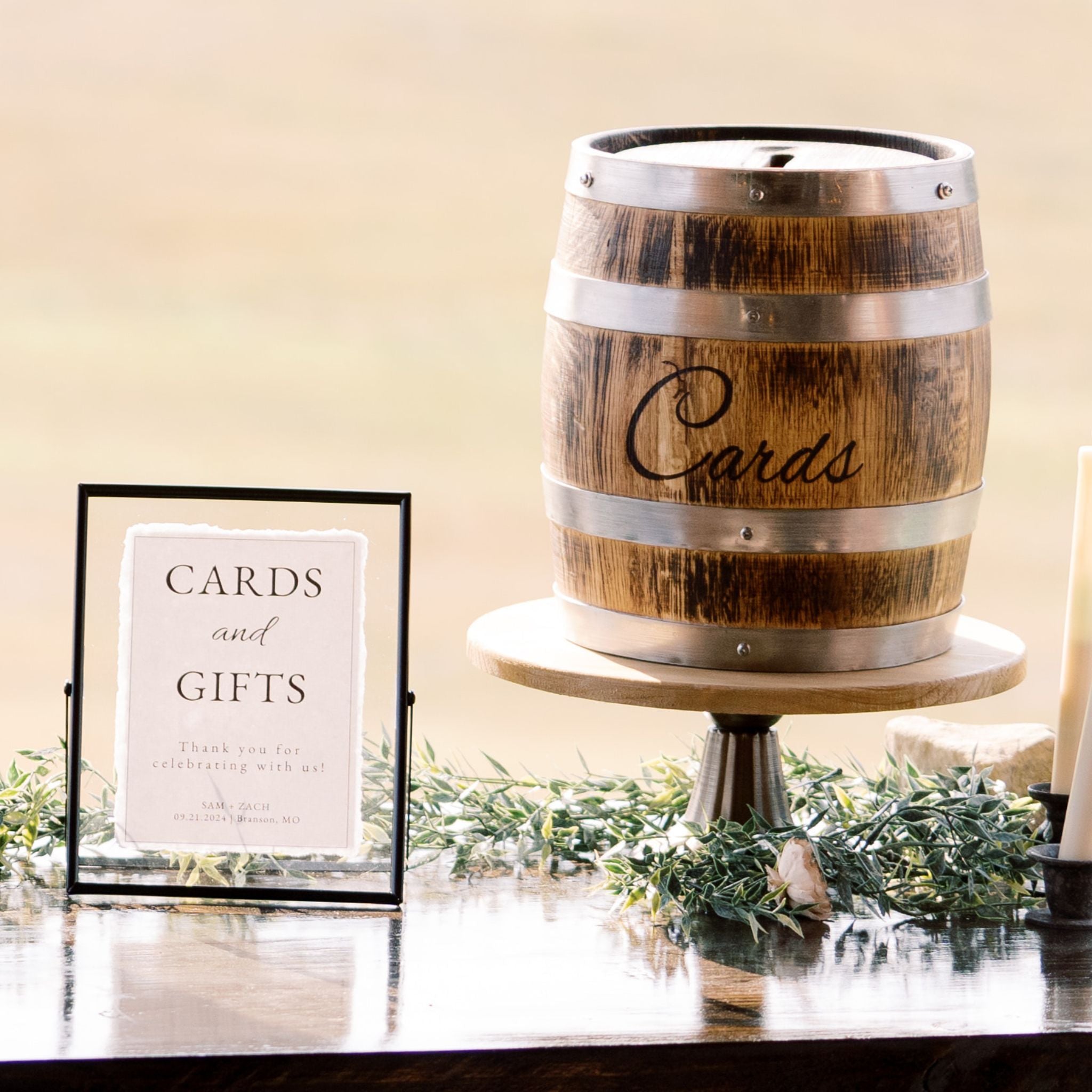 Whiskey barrel card holder on top of a flared pedestal with black floating picture frame or rent - Picture Perfect Rentals