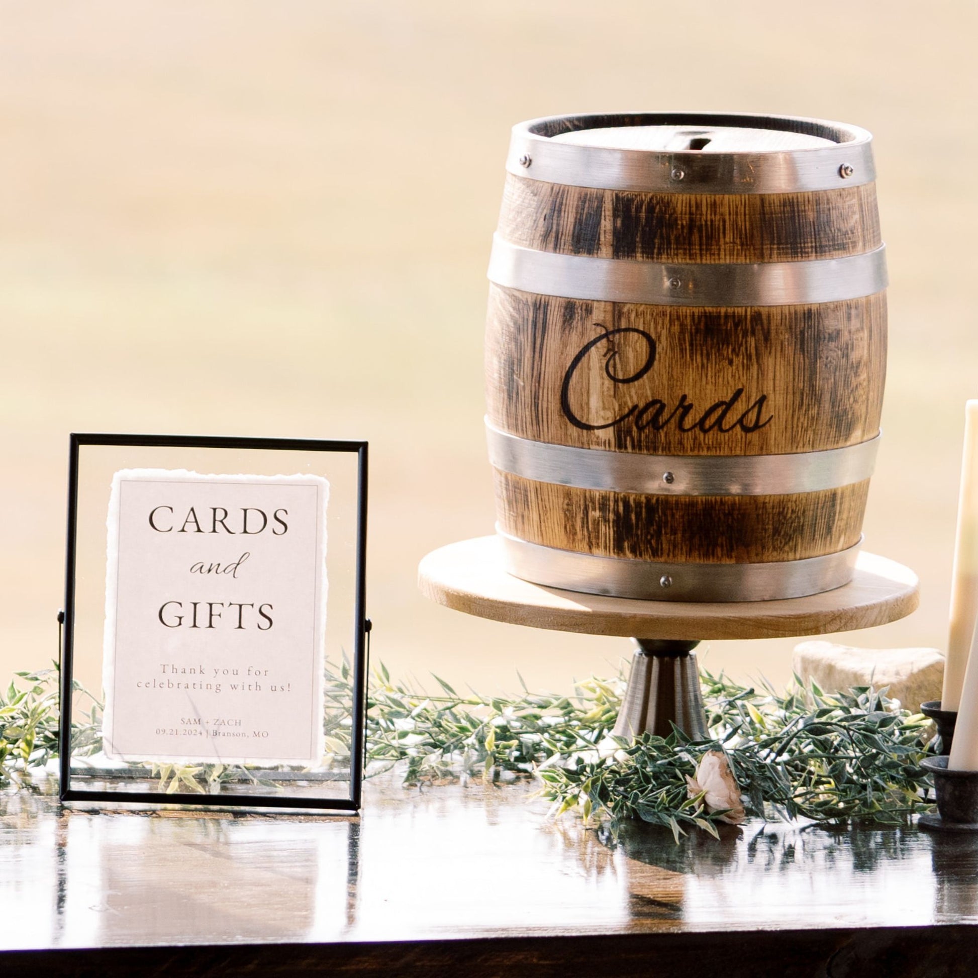 Whiskey barrel card holder on top of a flared pedestal with black floating picture frame or rent - Picture Perfect Rentals